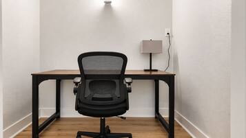 Ein Büro im Eck mit Schreibtisch, Stuhl und Wandlampe.