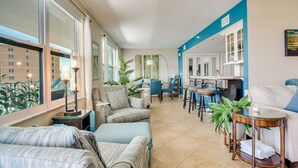 Amplia sala de estar con sofá, sillones, mesa de comedor y zona de cocina.