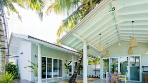 Una casa moderna con un porche cubierto, ventanas amplias y una escalera que lleva a un balcón.