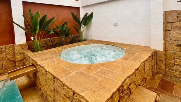 Ein Whirlpool mit Steinwänden und einem Pool.