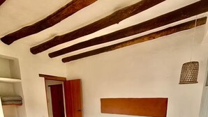 Ein Schlafzimmer mit einem Bett, einem hölzernen Kopfteil, einer roten Tür und einem Regal.
