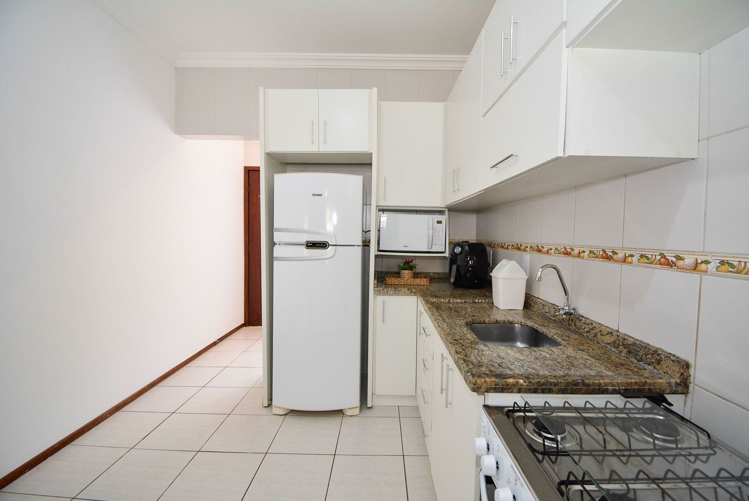 A kitchen with white cabinets, a built-in microwave, a gas stove, and a sink.