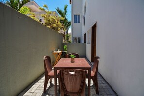 A patio with a table and chairs, a potted plant, and a small table with a glass. - Refúgio do Mar Centrinho Ingleses-NIN017 (Florianópolis)