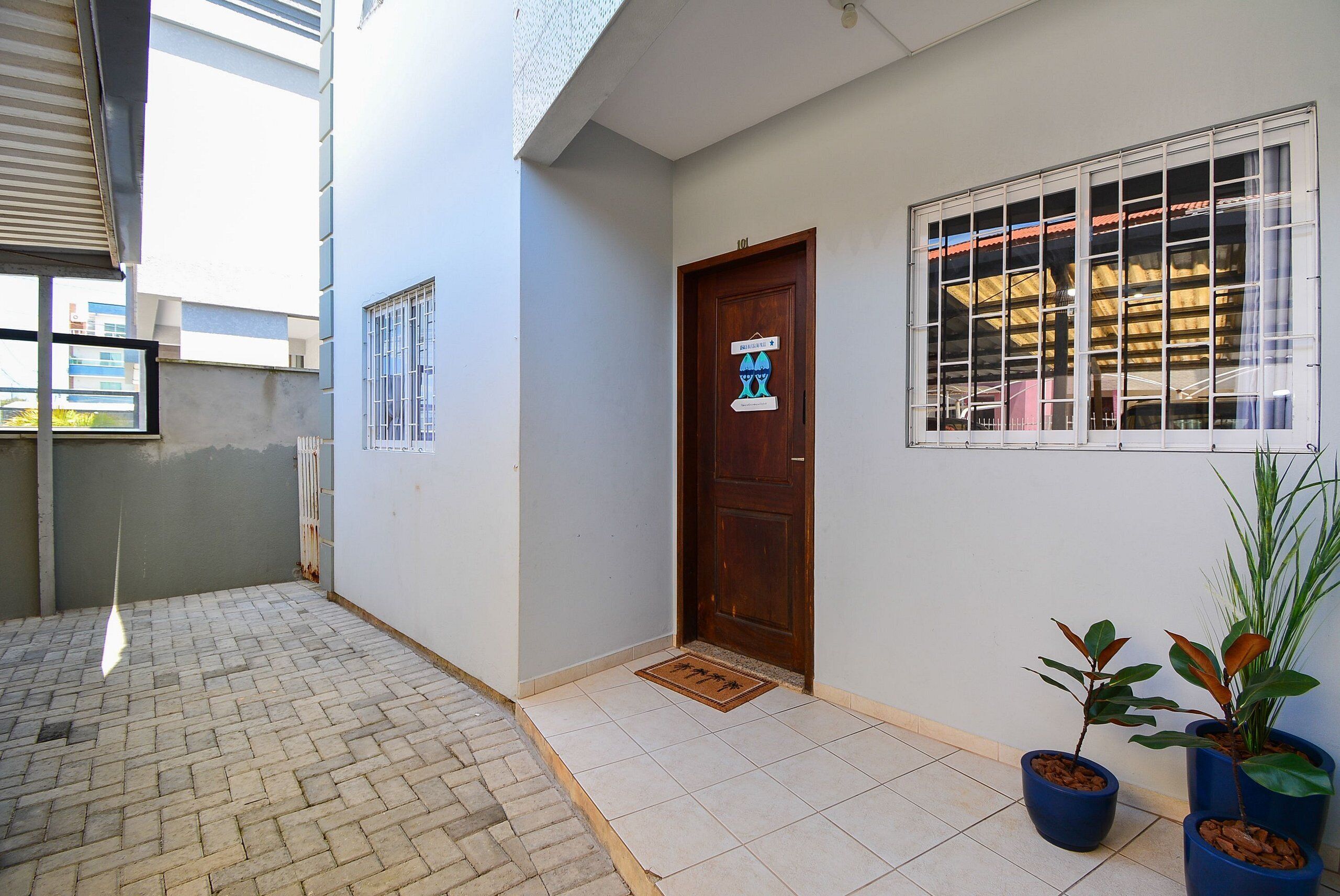 A clean, well-maintained entrance with a tiled floor, a wooden door, and potted plants.