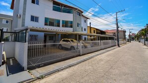 A multi-story residential building with a gated driveway and parked cars. - Refúgio do Mar Centrinho Ingleses-NIN017 (Florianópolis)