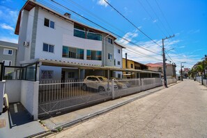 A multi-story residential building with a gated driveway and parked cars. - Refúgio do Mar Centrinho Ingleses-NIN017 (Florianópolis)