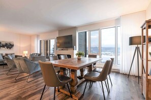 Ein moderner Essbereich mit Holztisch und Stühlen, einem Flachbildfernseher und großen Fenstern mit Blick.