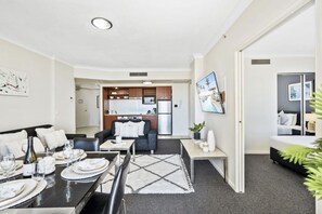 A modern apartment with a dining area, living room, and kitchenette. - Chevron Renaissance - 2 Bed 1 bath Low Floor - 1098 - 3 night - Chevron 2 Bedroom 1 Bathroom Apartment (Surfers Paradise)