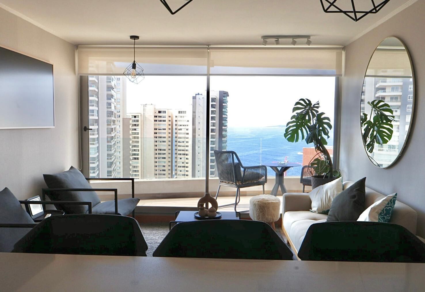 A modern living room with a large window overlooking a cityscape and the ocean.
