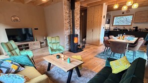Un salon chaleureux avec une cheminée, des sièges confortables, un téléviseur et un coin repas.