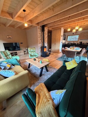 A cozy living room with a fireplace, comfortable seating, a TV, and a dining area. - New chalet, absolute calm & mountain views - Near La Clusaz & Grand-Bornand (Saint-Jean-de-Sixt)