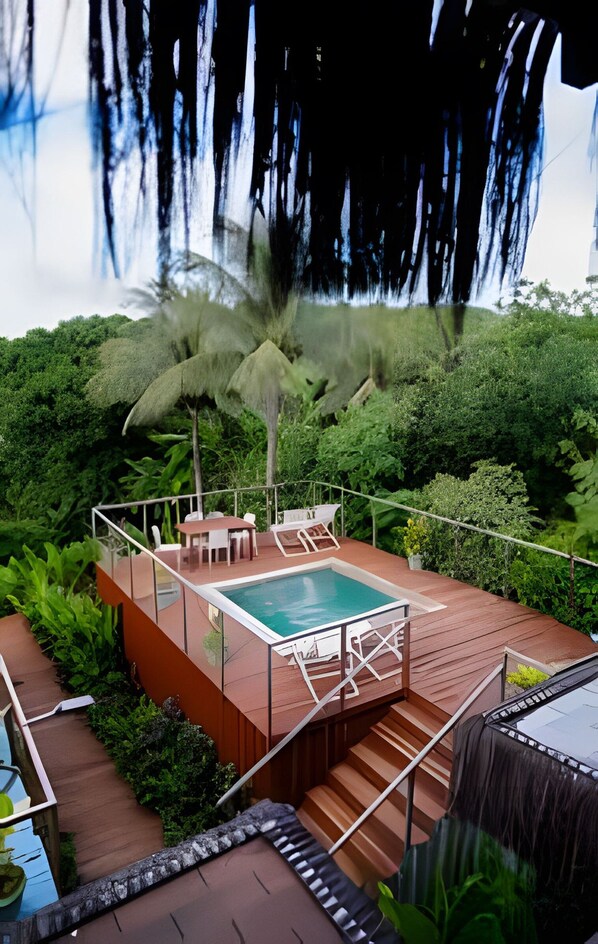 A rooftop pool area with a glass balustrade, a seating area, and a staircase leading down.