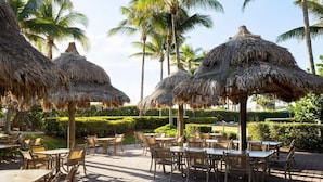A resort with thatched umbrellas and outdoor seating. - Ocean-Side 1BR Villa at Marriott’s Ocean Pointe - Balcony, Full Kitchen & Luxury (Palm Beach Shores)