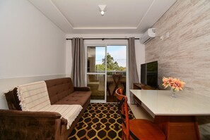 A modern living room with a sofa, a dining table, and a TV. - Apartamento Praia dos Ingleses - NIN015 (Florianópolis)