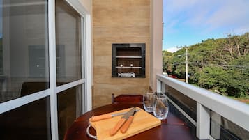 Uma varanda com uma mesa de madeira, tábua de corte, duas facas e dois copos.