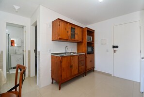Une cuisine avec des meubles de rangement en bois, un évier et un four  à micro-ondes.