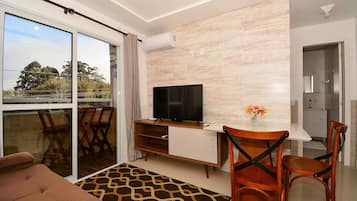 Una sala de estar moderna con sofá, televisor, mesa de comedor, sillas y una alfombra estampada.