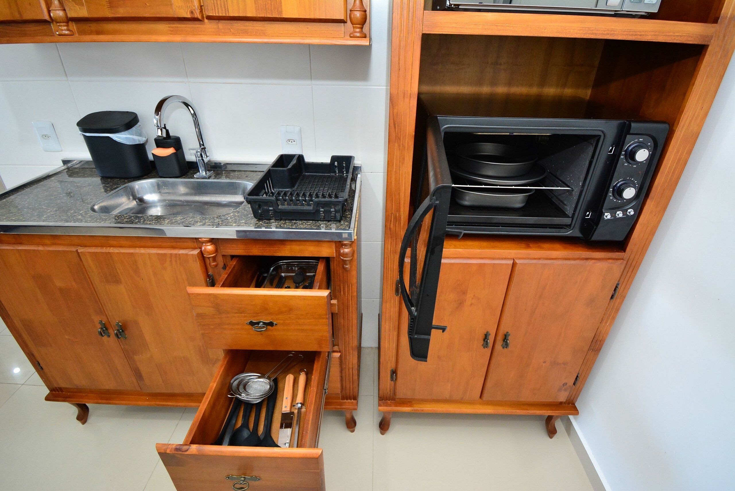 A compact kitchen with a sink, a toaster oven, and wooden cabinets.