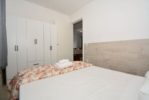 Une chambre à coucher avec un lit, une armoire et une salle de bain visible à travers une porte ouverte.