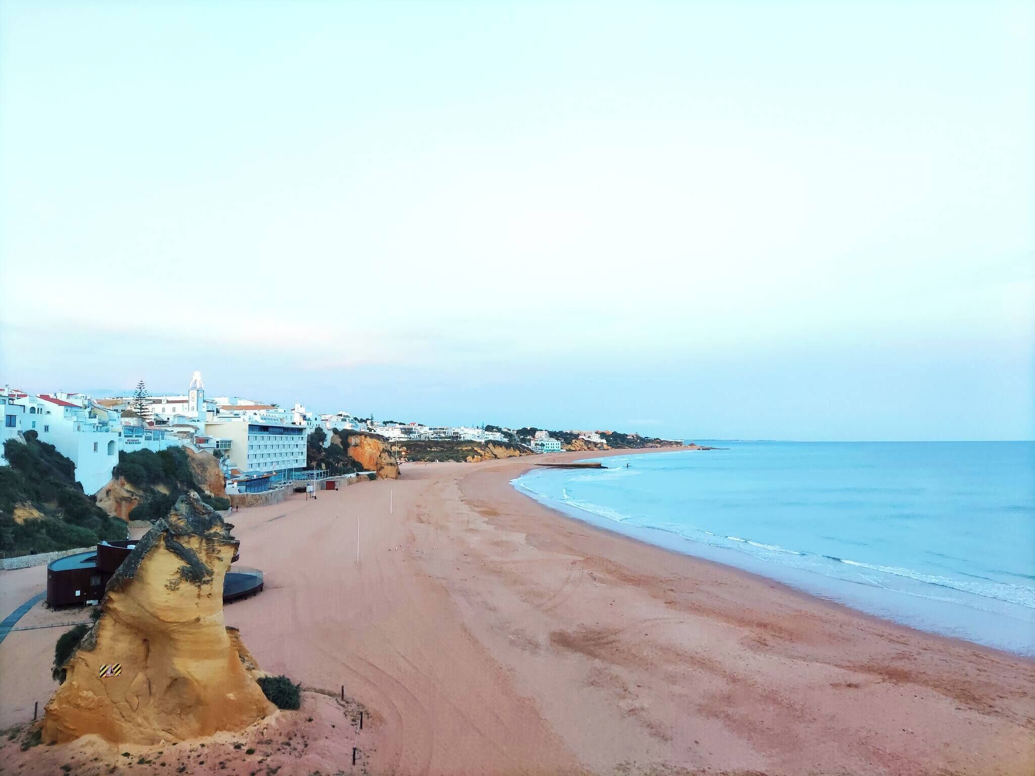 Eine Küstenstadt mit Sandstrand, Gebäuden und einem Felsen.