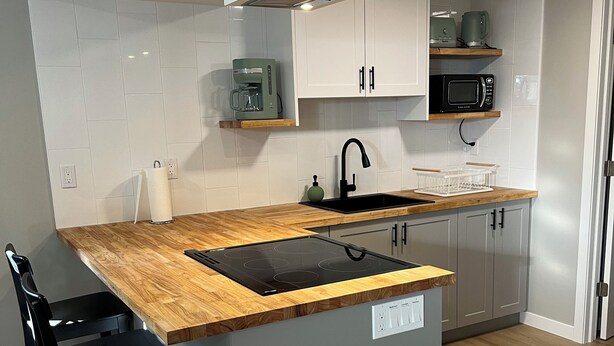 A modern kitchen with a wooden countertop, black sink, and grey cabinets. - Bright & Cozy Basement Suite – Perfect for Work or Adventure (Fort Saskatchewan)