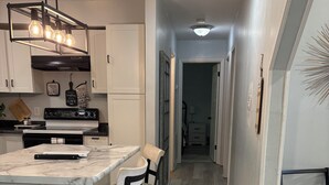 Et moderne køkken med bordplade i marmor, indbygget ovn og hængende lampeskærm.