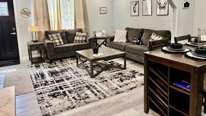 En moderne stue med to sofaer, et sofabord, et fjernsyn og en ventilator i loftet.