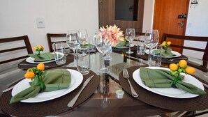 A dining table set with green napkins, white plates, and clear glassware.