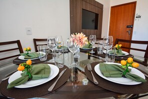 A dining table set with green napkins, white plates, and clear glassware. - Amplo Apartamento Praia Ingleses -NIN013 (Florianópolis)