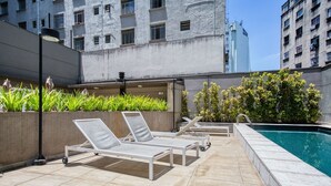 A rooftop pool area with lounge chairs and a swimming pool. - Apartamento na S c Academia Piscina e Smart Lock (São Paulo)
