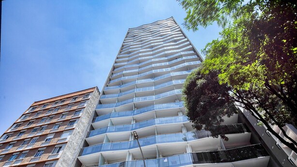 A high-rise building with multiple balconies, a modern architectural design, and a clear sky. - Apartamento na S c Academia Piscina e Smart Lock (São Paulo)