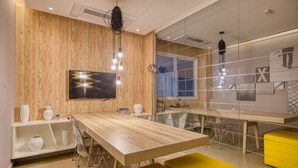 A modern kitchen with wooden walls, a large wooden table, yellow chairs, and a TV mounted on the wall. - Apartamento na S c Academia Piscina e Smart Lock (São Paulo)