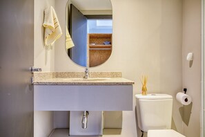 A bathroom with a white sink, a mirror, a toilet, and a towel hanging on the wall. - Apartamento na S c Academia Piscina e Smart Lock (São Paulo)