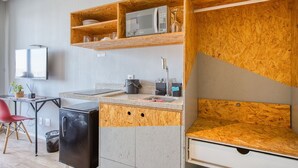 A compact kitchen with a microwave, sink, and wooden shelves. - Apartamento na S c Academia Piscina e Smart Lock (São Paulo)