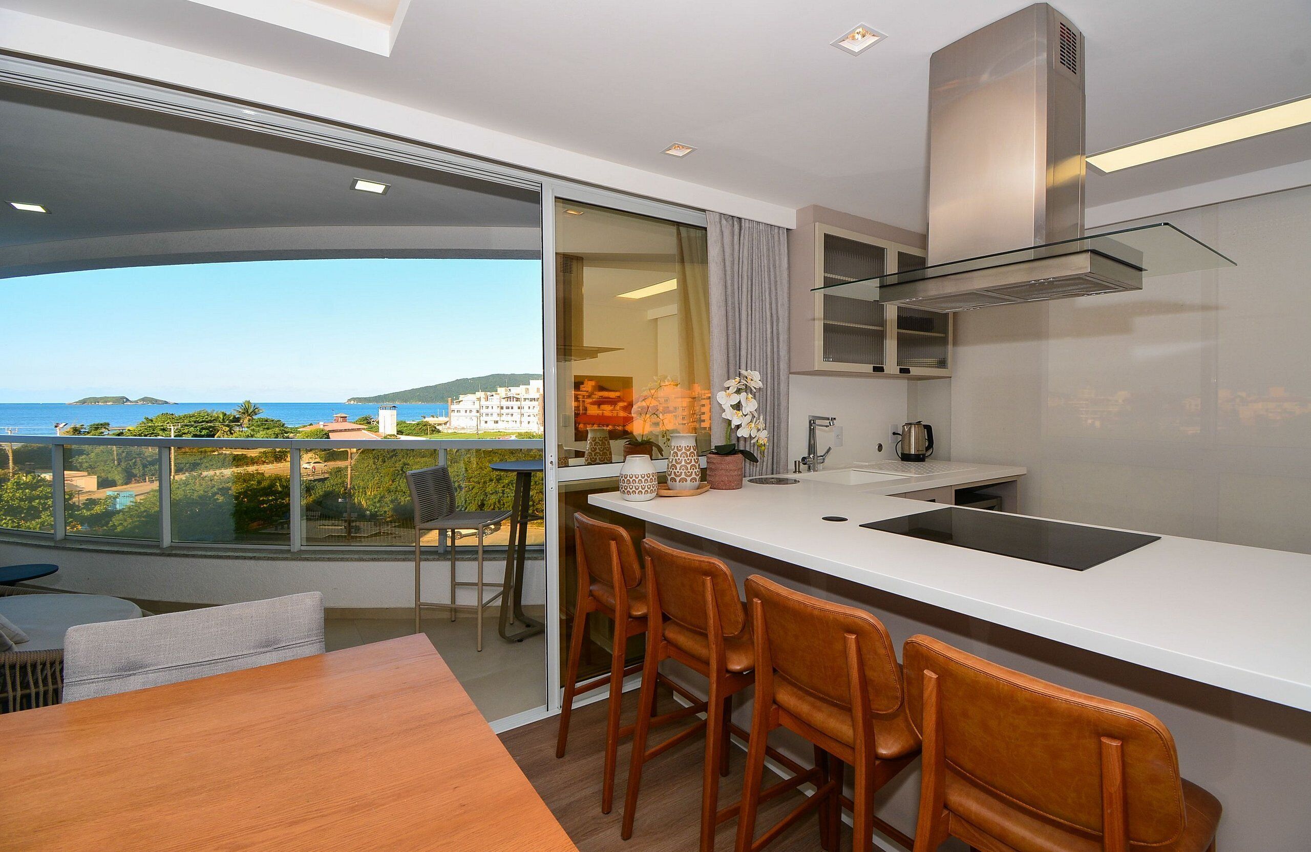 A modern kitchen with a large island, bar stools, and a view of the sea.
