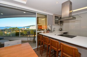A modern kitchen with a large island, bar stools, and a view of the sea. - Gaivotas Golden Luxo a 200m praia-NIN012 (Florianópolis)