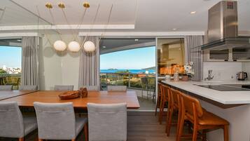 A modern kitchen with a large island, a dining area with a table and chairs, and a view of the ocean.