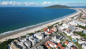A coastal town with a beach, buildings, and a mountain in the distance.