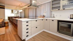 Une cuisine moderne dotée d’un îlot central, d’un four encastré et d’un coin repas avec des chaises.