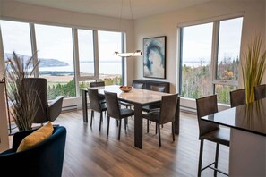Ein modernes Esszimmer mit großem Tisch, Stühlen und Blick ins Freie.