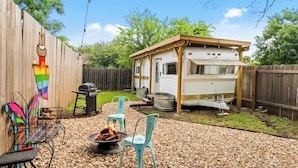 A backyard with a barbecue grill, two chairs, a small shed, and a wooden fence. - Rhonda the Rambler- Glamp w/Pets (Austin)