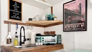 A compact kitchen with a wooden countertop, a coffee maker, a toaster, and a teal cabinet. - Rhonda the Rambler- Glamp w/Pets (Austin)