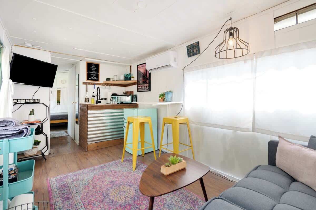 A compact living space with a kitchenette, a sofa, a coffee table, and a TV.