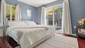 Quarto com cama, janela grande, lareira e vista para o exterior.