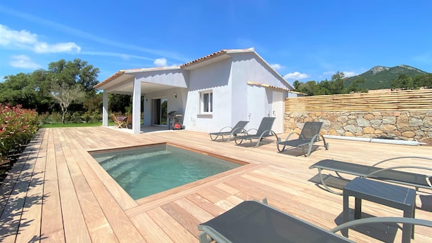 Uma villa moderna com piscina, área de estar externa e uma parede de pedra.