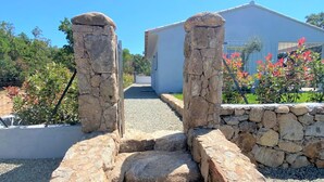 Uma trilha de pedra leva a um edifício moderno com fachada branca e uma parede de pedra em um dos lados.