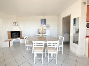 Ein Essbereich mit einem runden Tisch, weißen Stühlen, einer Uhr und einem Kamin.