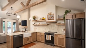 Una cocina moderna con armarios de madera, un refrigerador de acero inoxidable, horno integrado y una isla grande con pileta.