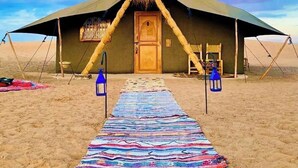 A desert tent with a wooden door, a colorful rug leading to it, and two lanterns on either side. - Beautiful 1-bedroom campground in Merzouga for a peaceful escape (Merzouga)
