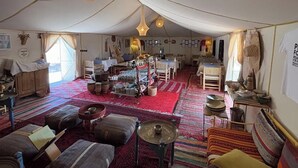 A tented accommodation with a central dining area, multiple seating options, and a variety of decorative items. - Beautiful 1-bedroom campground in Merzouga for a peaceful escape (Merzouga)